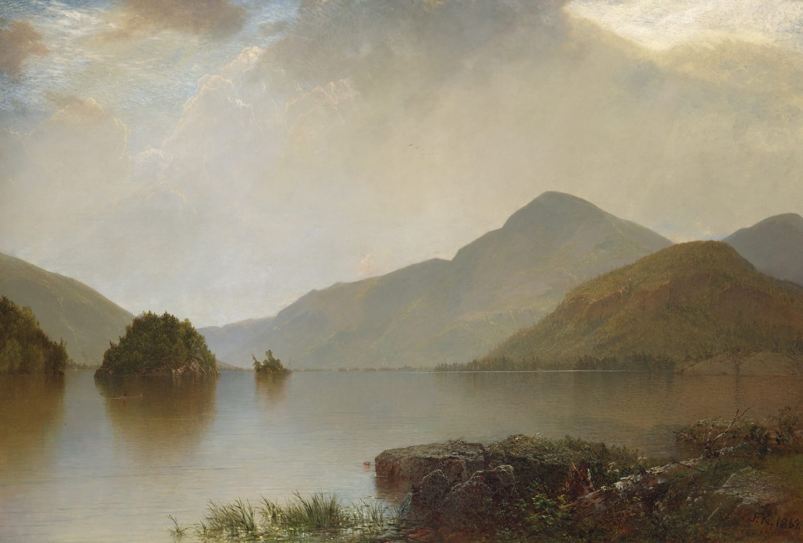 Still water stretching to soft blue mountains, with small wooded islands and a rocky shore in the foreground.
